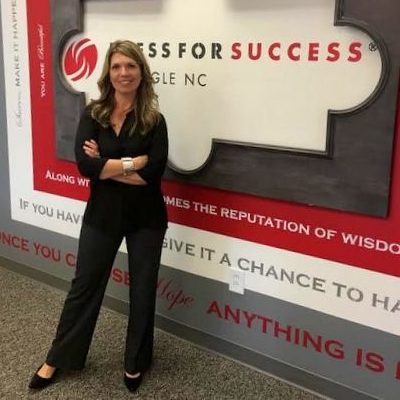 Mir Garvy standing in front of Dress For Success sign. She believes so much in the power of a polished LinkedIn profile that she volunteers her time to speak to non-profit groups.